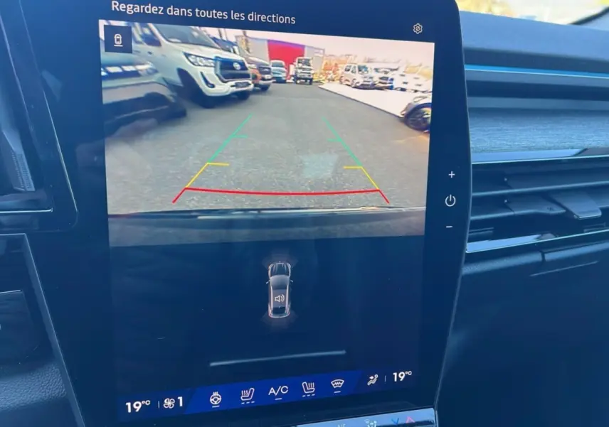 Écran central du Renault Austral E-Tech 200 Techno 2025 montrant la caméra de recul avec vue arrière et lignes de guidage colorées.