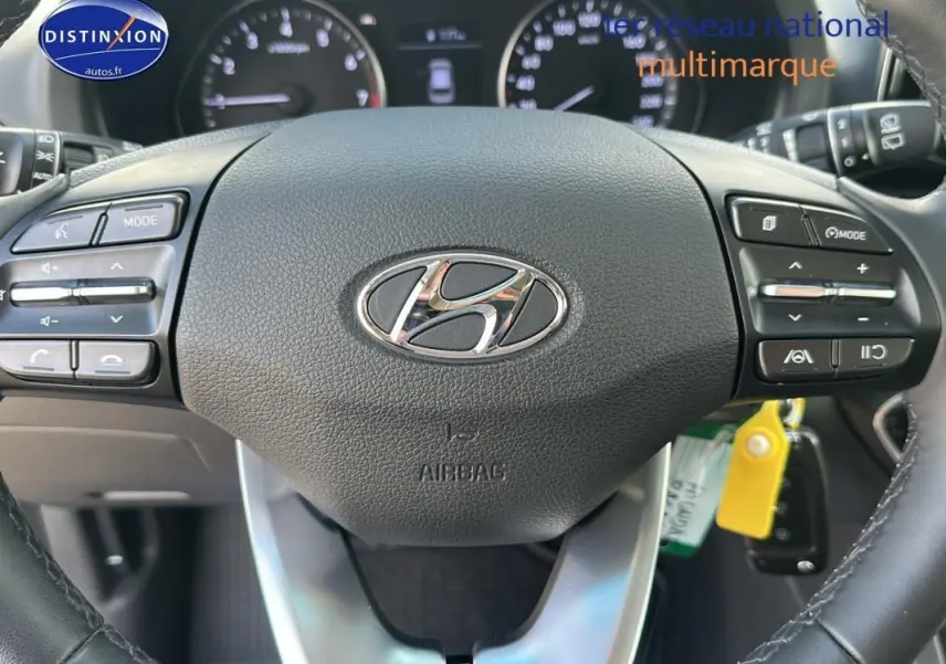 Vue rapprochée du volant noir de la Hyundai i30 SW 2022 avec commandes intégrées et logo central chromé.