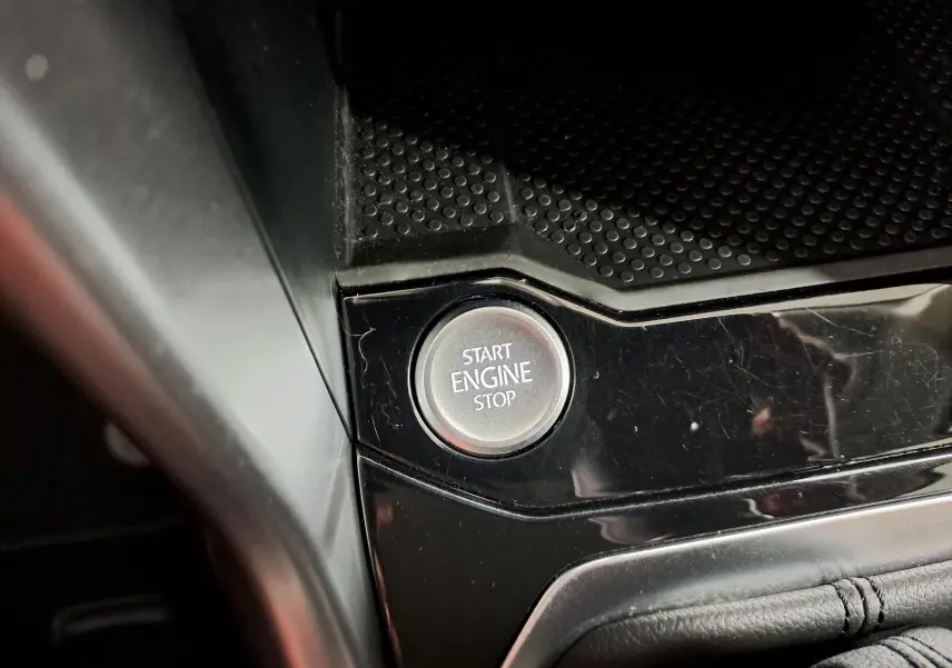 Bouton start/stop moteur en gros plan sur la console noire brillante du Volkswagen T-Roc 2024.