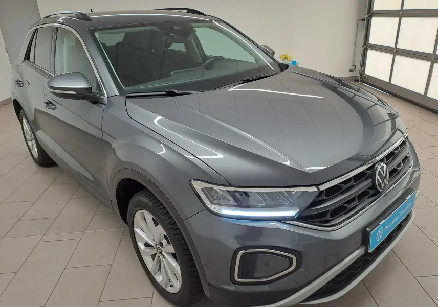 Volkswagen T-Roc gris Indium en 3/4 avant droit, avec jantes alliage 17'' Johannesburg et feux LED allumés.