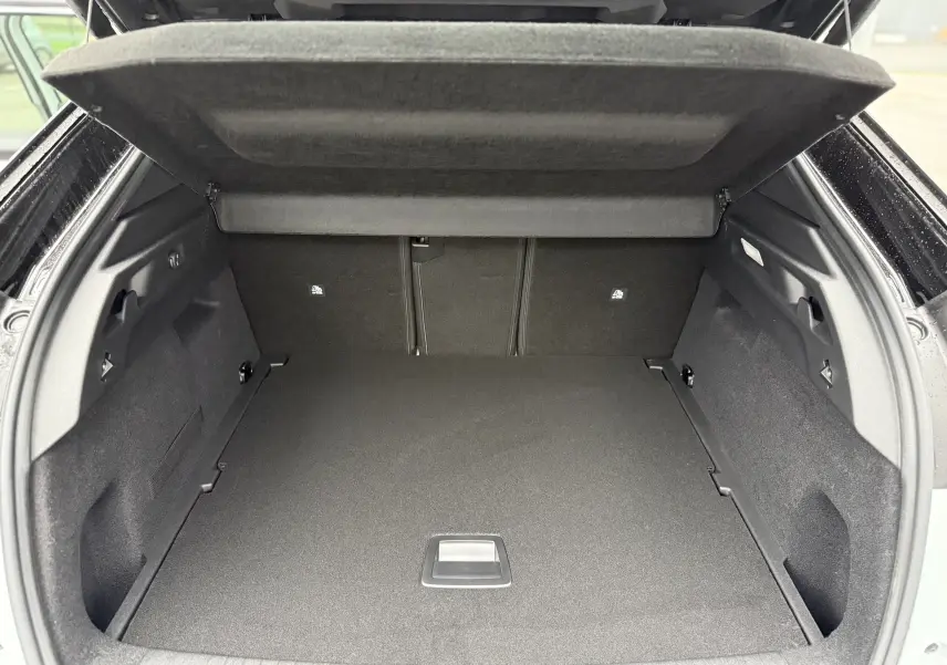 Coffre ouvert du Peugeot 3008 Hybrid blanc, vue arrière montrant un espace de chargement spacieux et bien fini.