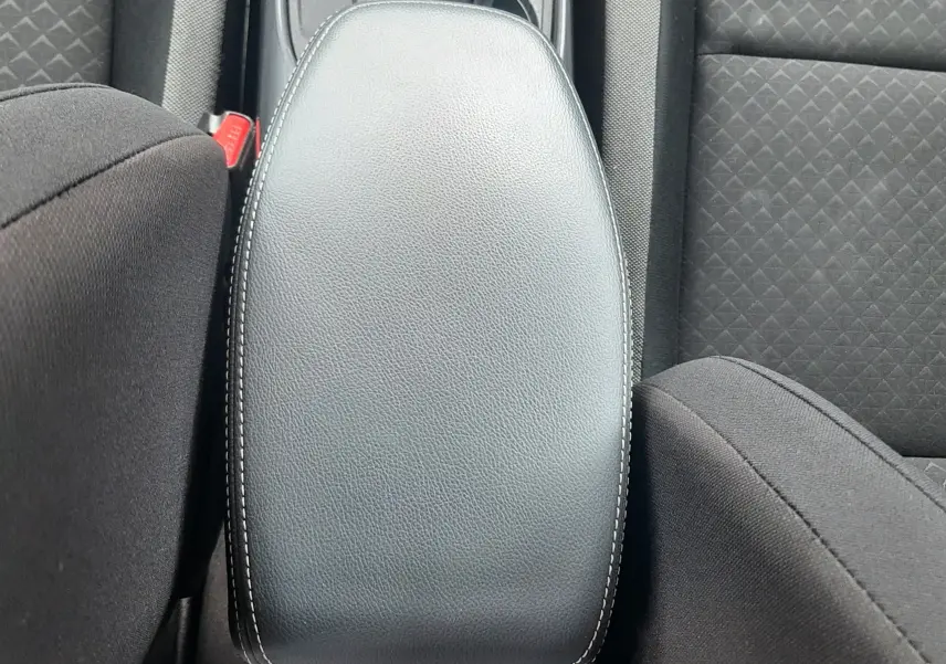 Vue plongeante sur l'accoudoir central noir et les sièges en tissu gris du Nissan Juke 2020 intérieur.