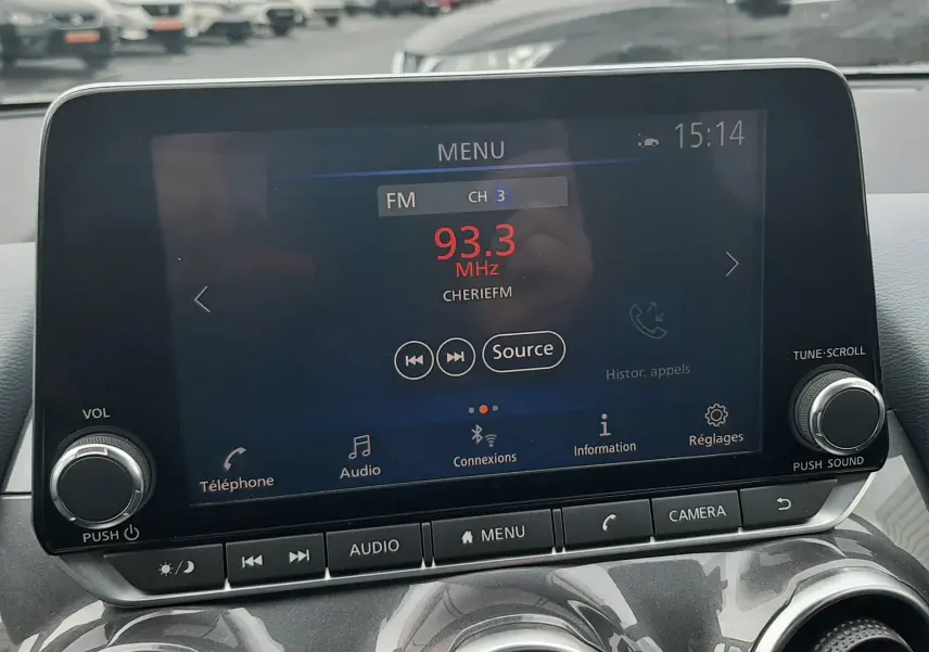 Vue intérieure centrée sur l'écran tactile multimédia du Nissan Juke gris 2020, avec commandes audio et climatisation visibles.