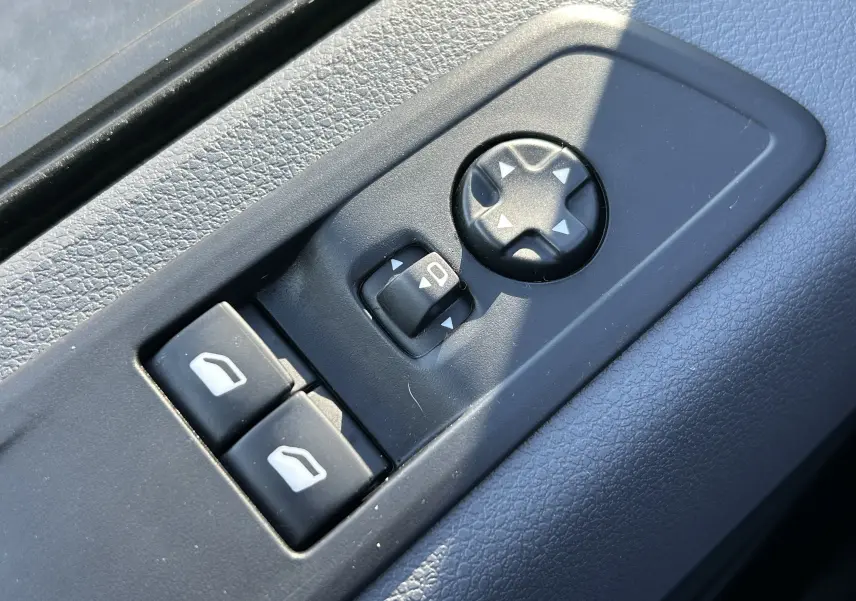 Gros plan sur les commandes de réglage des rétroviseurs et des vitres électriques côté conducteur d’un Citroën Jumpy blanc.