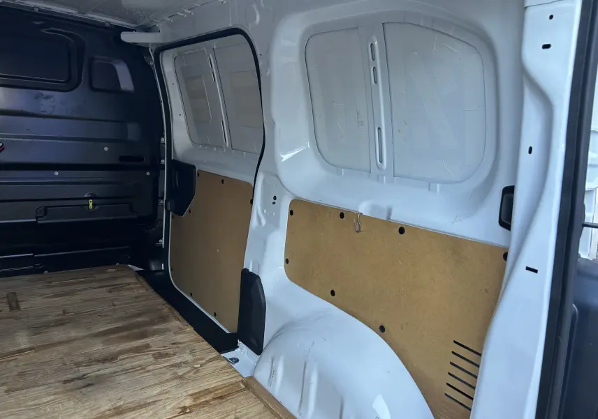 Intérieur du fourgon blanc Citroën Jumpy vu côté droit, avec plancher en bois et parois partiellement protégées.
