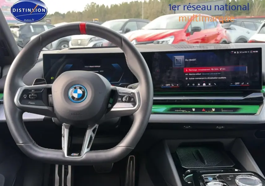 Vue intérieure centrée sur le volant sport BMW noir et l'écran tactile large du tableau de bord de la Série 5 i5 M60.
