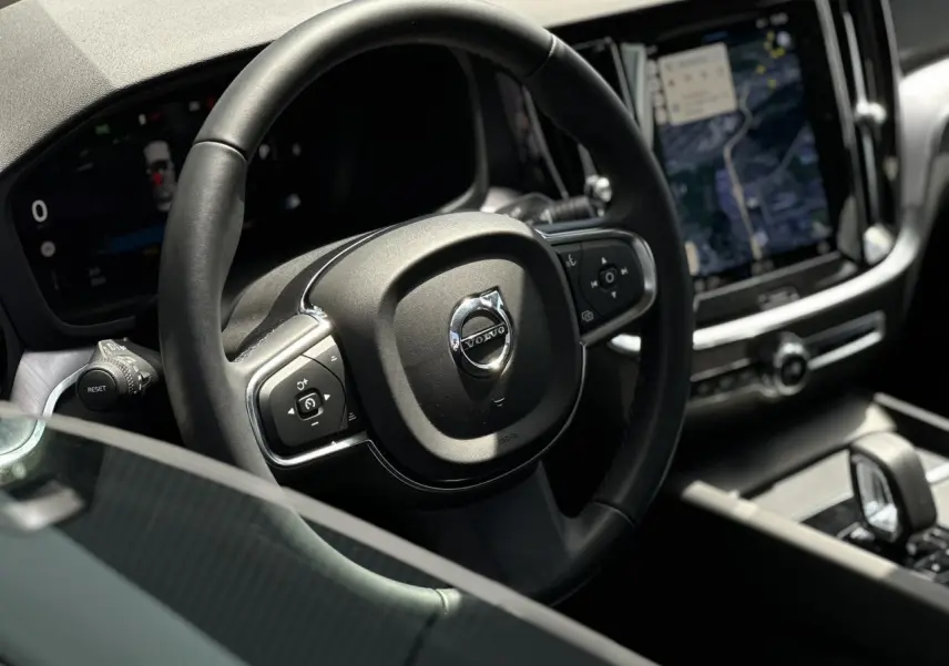 Intérieur du Volvo S60 B4 2024, vue rapprochée du volant avec commandes intégrées et écran tactile multimédia.