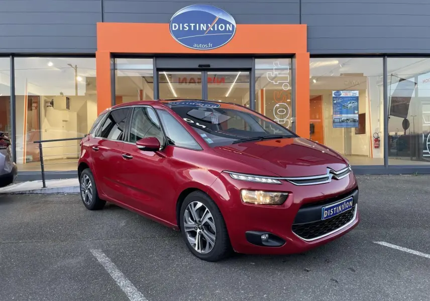 Citroën C4 Picasso rouge foncé vue 3/4 avant droit devant un showroom Distinxion.