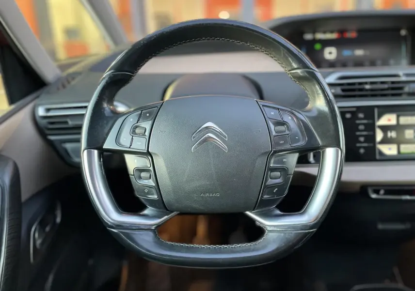 Gros plan sur le volant multifonction noir du Citroën C4 Picasso 2014, avec tableau de bord et écran tactile en arrière-plan.