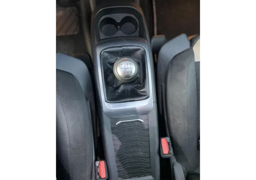 Le levier de vitesse manuel de la Citroën C4 Picasso 2014 vu de dessus entre les sièges noirs.