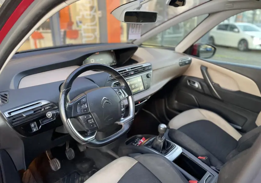Intérieur de la Citroën C4 Picasso 2014 vu côté conducteur, volant multifonction et sellerie bicolore noire et beige.