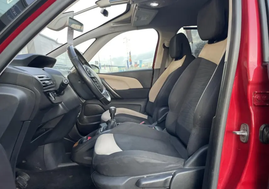Intérieur avant du Citroën C4 Picasso rouge foncé 2014, sièges bicolores noirs et beige, volant et levier de vitesse manuelle visibles.