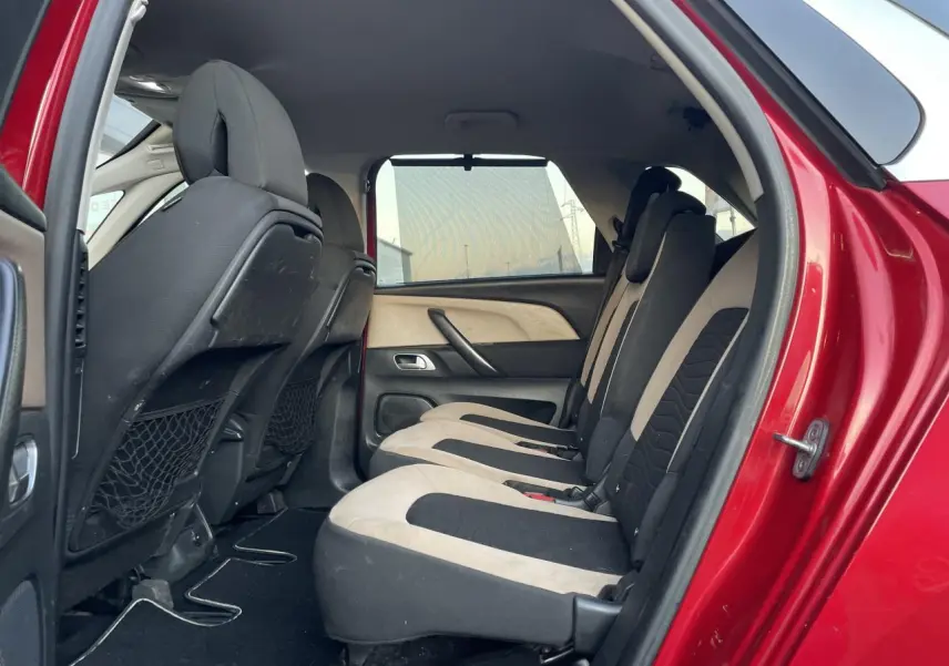 Vue latérale intérieure sur les sièges arrière bicolores d'une Citroën C4 Picasso rouge foncé de 2014.