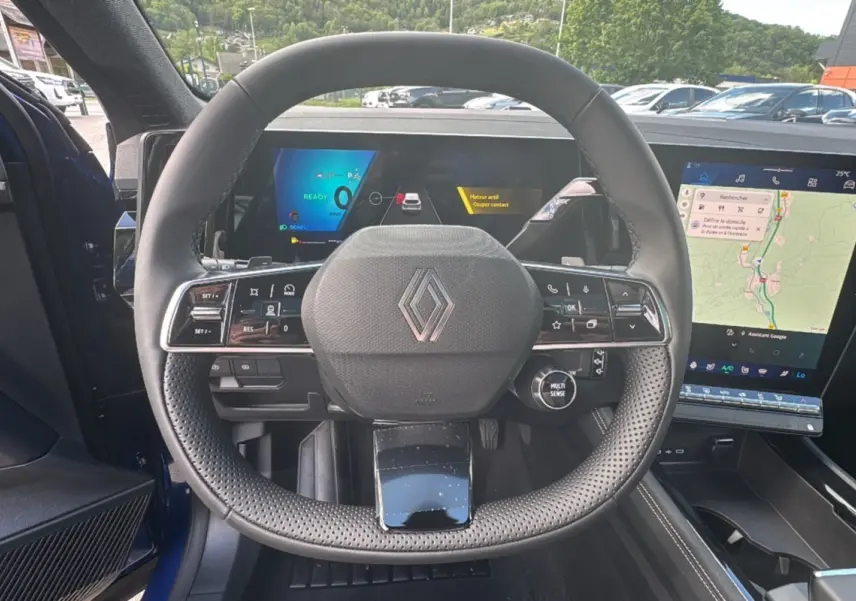 Vue intérieure centrée sur le volant perforé du Renault Austral E-Tech 200, avec tableau de bord numérique et écran tactile.