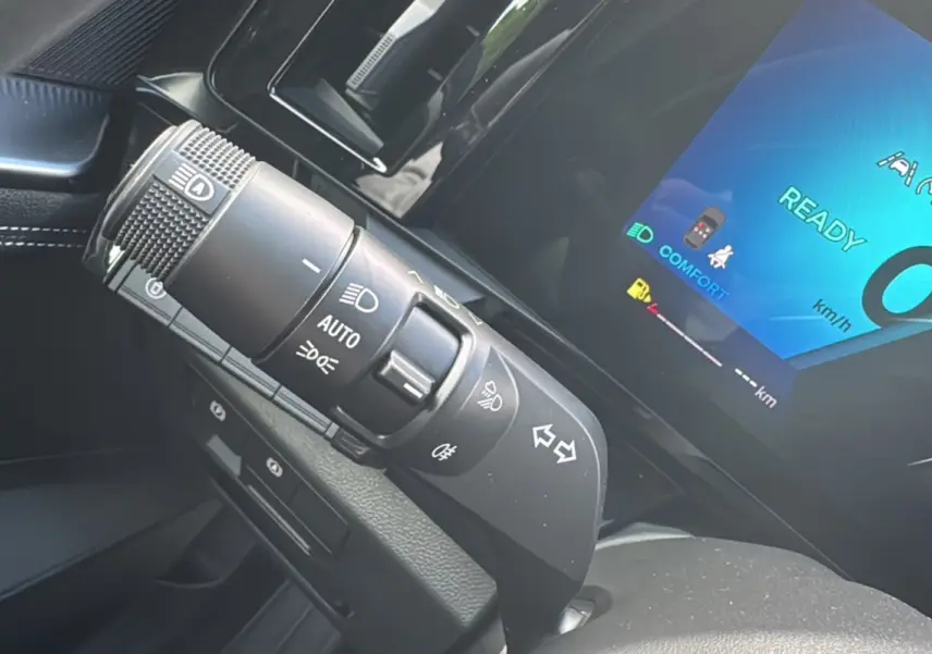 Gros plan sur la commande des phares et clignotants du Renault Austral E-TECH 200 bleu iron avec tableau de bord digital allumé.
