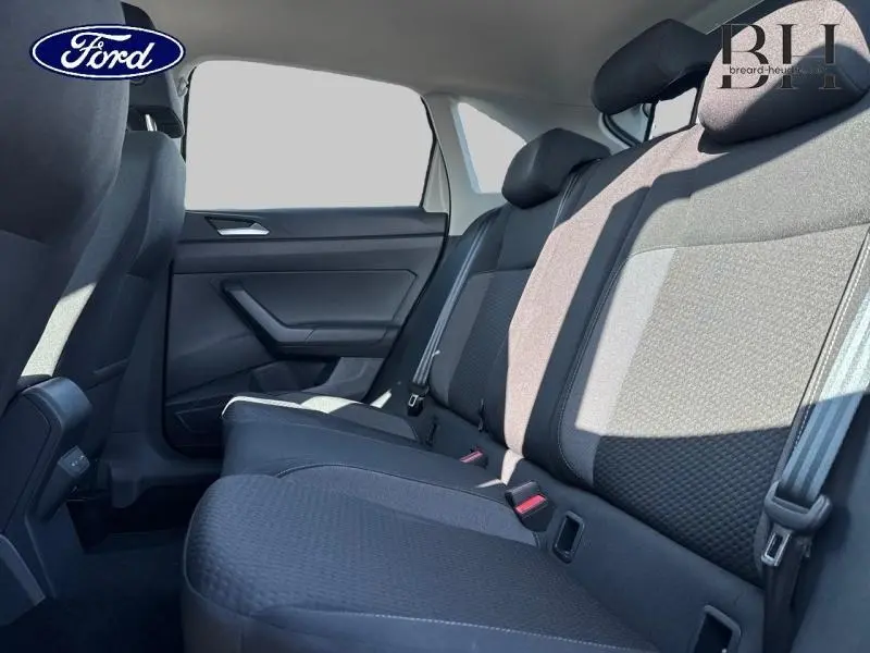 Vue côté gauche de la banquette arrière en tissu noir du Volkswagen Taigo 2024, avec ceintures de sécurité visibles.