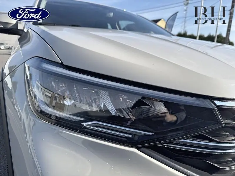 Gros plan sur le phare avant gauche du Volkswagen Taigo blanc pur, soulignant ses lignes modernes et détails chromés.