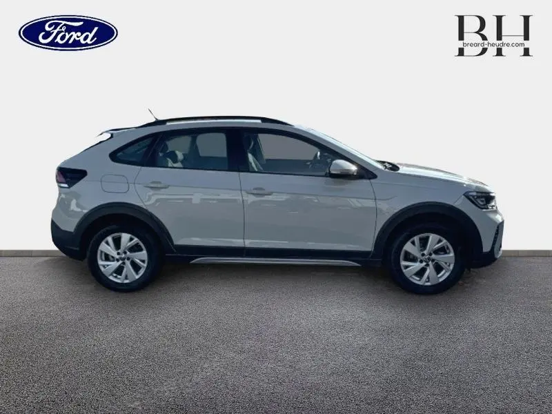 Profil côté gauche d'un Volkswagen Taigo blanc pur 2024 avec barres de toit et jantes alu visibles