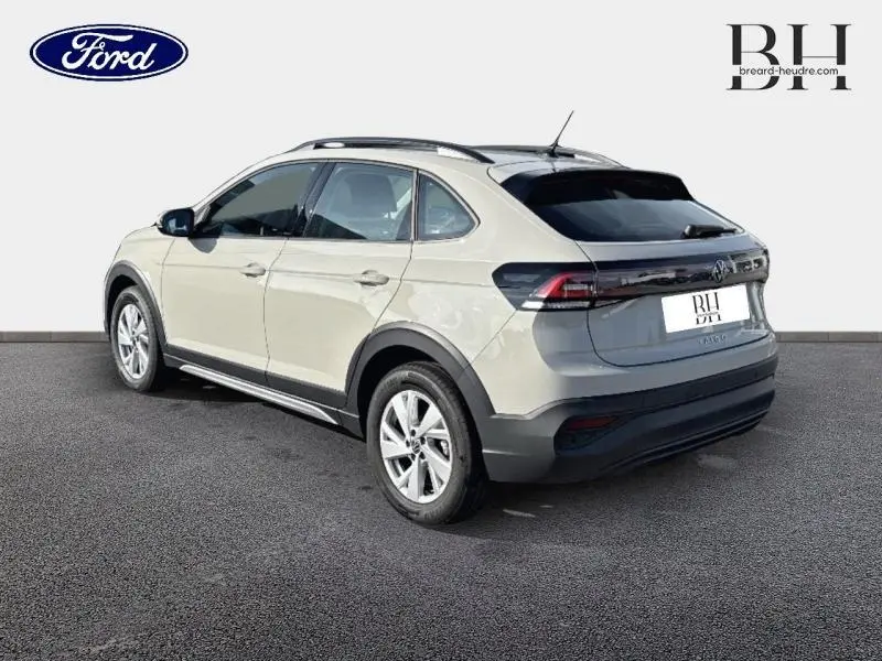 Vue 3/4 arrière droite d'un Volkswagen Taigo blanc pur 2024 avec barres de toit et jantes alu.