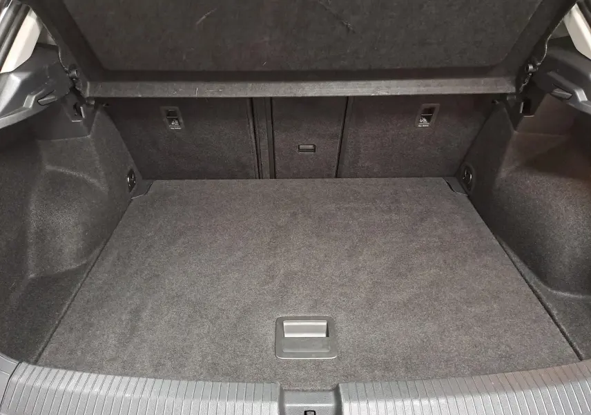 Coffre ouvert du Volkswagen T-Roc 1.5 TSI 150 DSG7 en gris Indium, montrant l'espace de chargement intérieur.