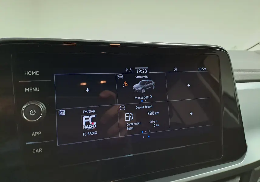 Écran tactile central du Volkswagen T-Roc 2024 affichant le statut véhicule et la radio FM, intérieur sobre et moderne.