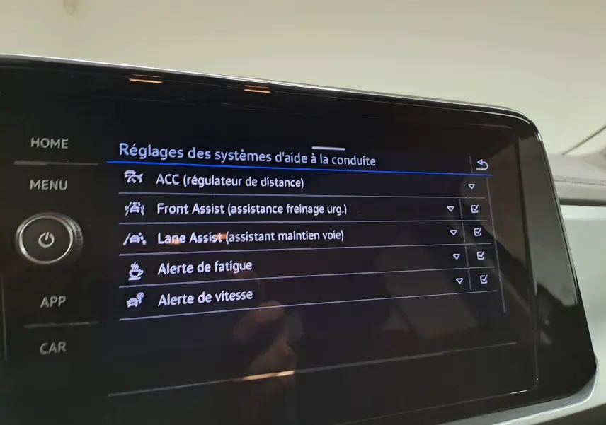 Écran tactile du système d'aide à la conduite du Volkswagen T-Roc 2024 affichant les réglages d'assistances activées.