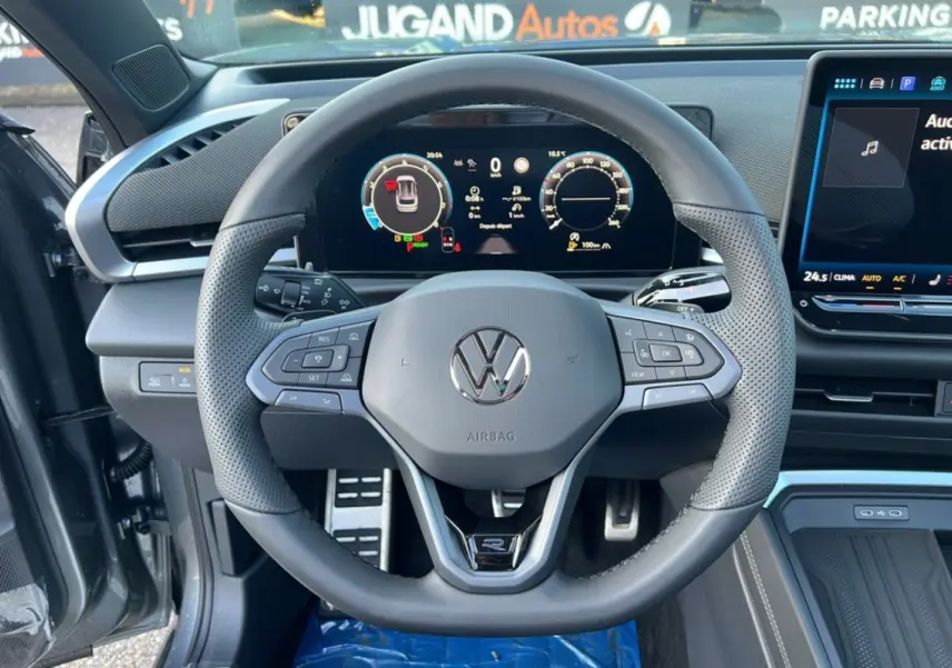Vue centrée sur le volant cuir perforé Volkswagen T-Roc R-Line gris loup avec tableau de bord digital et écran tactile.