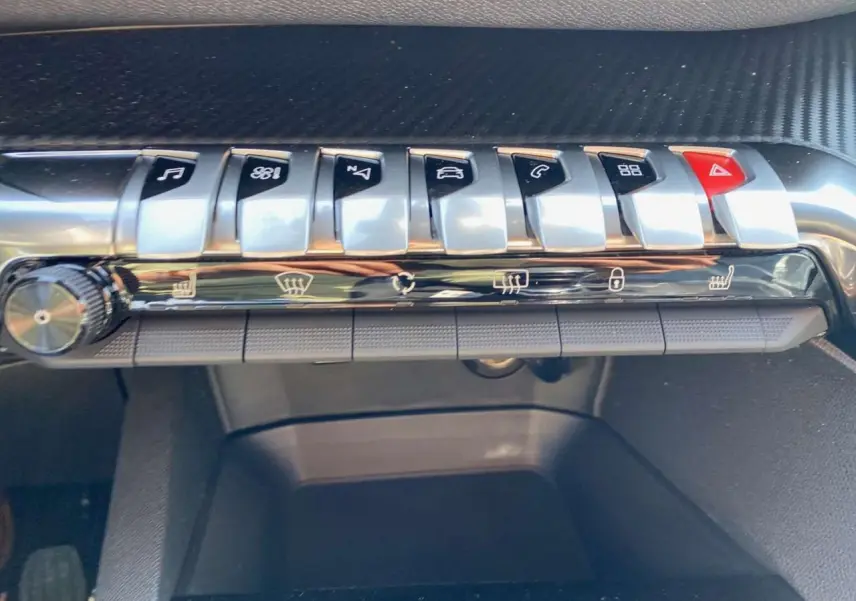 Gros plan sur la rangée de boutons de commande argentés et noirs du tableau de bord du Peugeot 3008 2023.