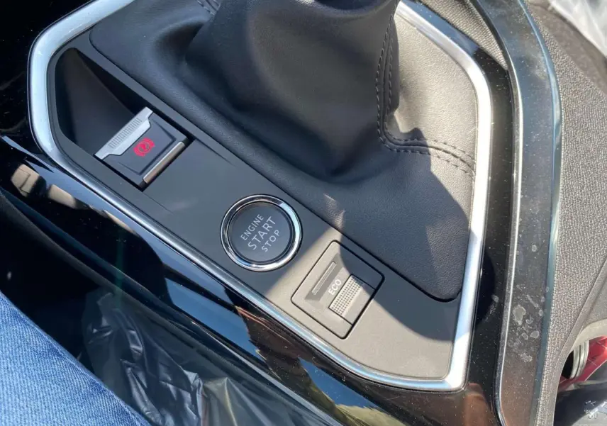 Gros plan sur la console centrale noire brillante du Peugeot 3008 2023 avec bouton start/stop et commande ECO.