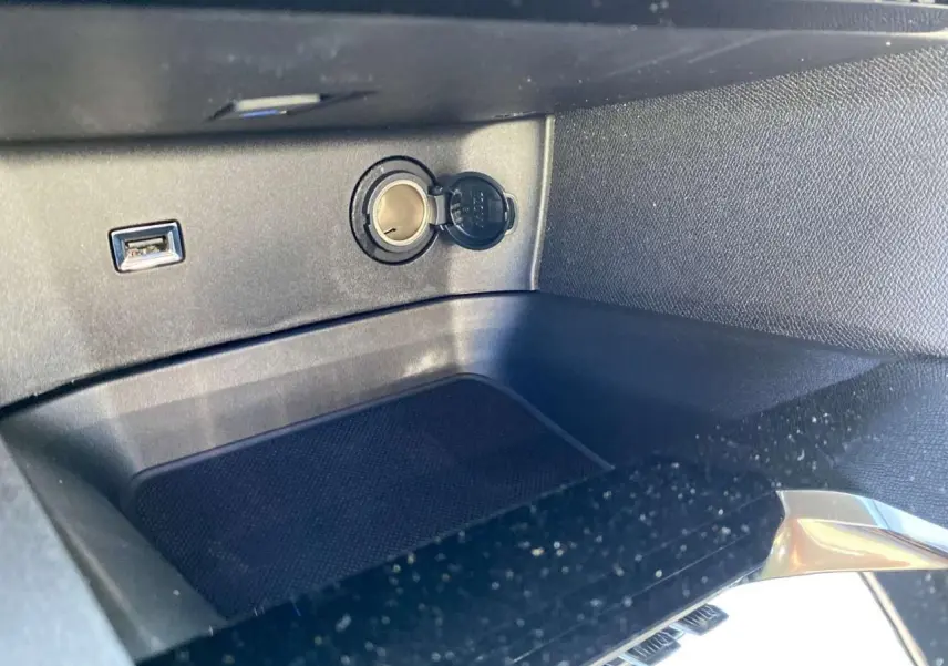 Prise allume-cigare et port USB dans le rangement central avant du Peugeot 3008 gris platinium 2023.