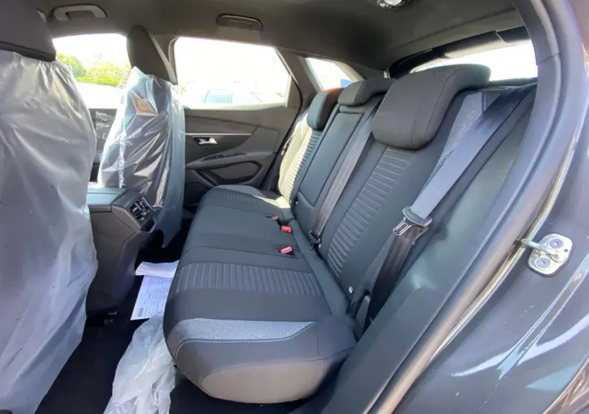 Vue intérieure côté droit des sièges arrière noirs du Peugeot 3008 2023 avec protections plastiques sur les sièges avant.
