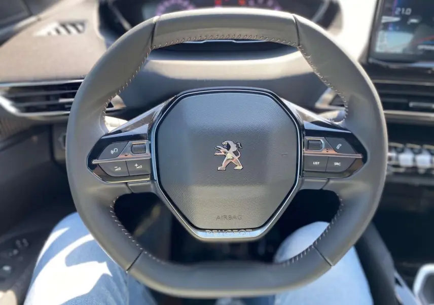 Volant compact multifonctions du Peugeot 3008 2023, vue frontale centrée sur le logo lion et commandes intégrées.