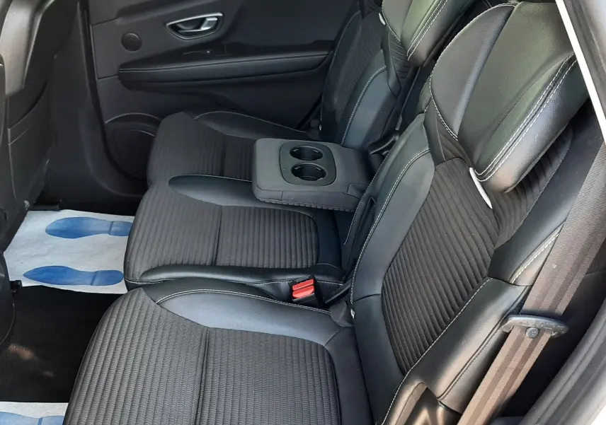 Vue latérale droite de l'intérieur arrière du Renault Scénic IV 2018, sièges noirs avec accoudoir central et porte ouverte.