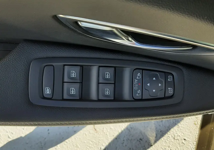 Commandes des vitres électriques et réglages des rétroviseurs sur la porte côté conducteur d'un Renault Scenic IV blanc nacré.