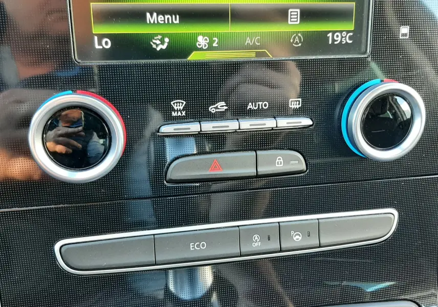 Gros plan sur la console centrale du Renault Scénic IV, mettant en valeur les commandes de climatisation et le bouton ECO.