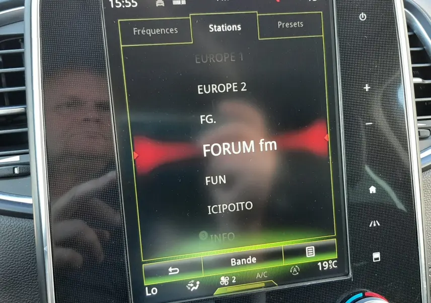 Écran tactile central du Renault Scénic IV affichant les stations radio FM avec commandes climatisation en dessous.