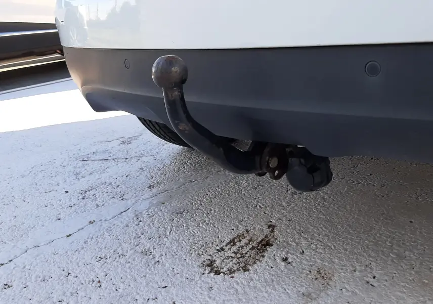 Gros plan sur l'attelage de remorque noir sous le pare-chocs arrière blanc nacré d'un Renault Scenic IV 2018.
