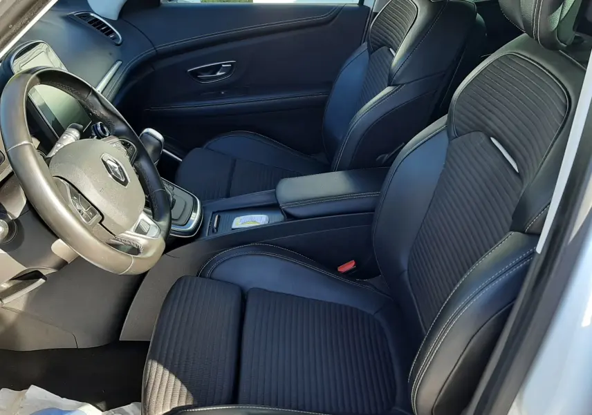 Intérieur avant droit du Renault Scenic IV blanc nacré, sièges noirs en tissu et cuir avec volant multifonction.