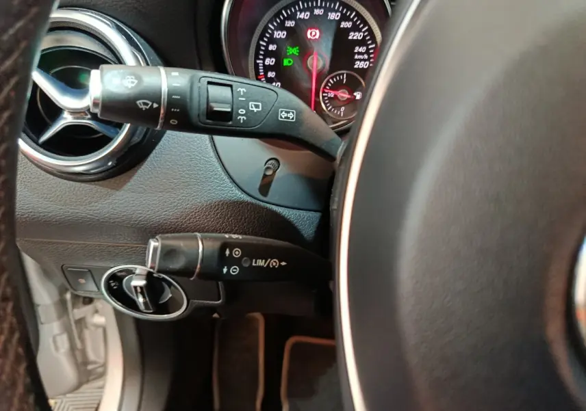 Vue rapprochée du volant cuir et des commandes au volant du Mercedes GLA 200 d gris clair, tableau de bord éclairé.