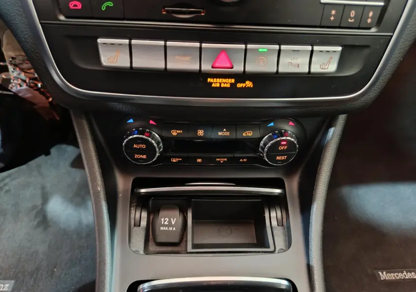 Vue rapprochée du tableau de bord central gris foncé du Mercedes GLA 200 d avec commandes climatisation et prise 12V.