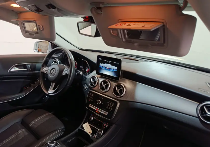 Intérieur du Mercedes GLA 200 d Business Executive 2018 vu côté conducteur, tableau de bord noir avec écran central et volant cuir.