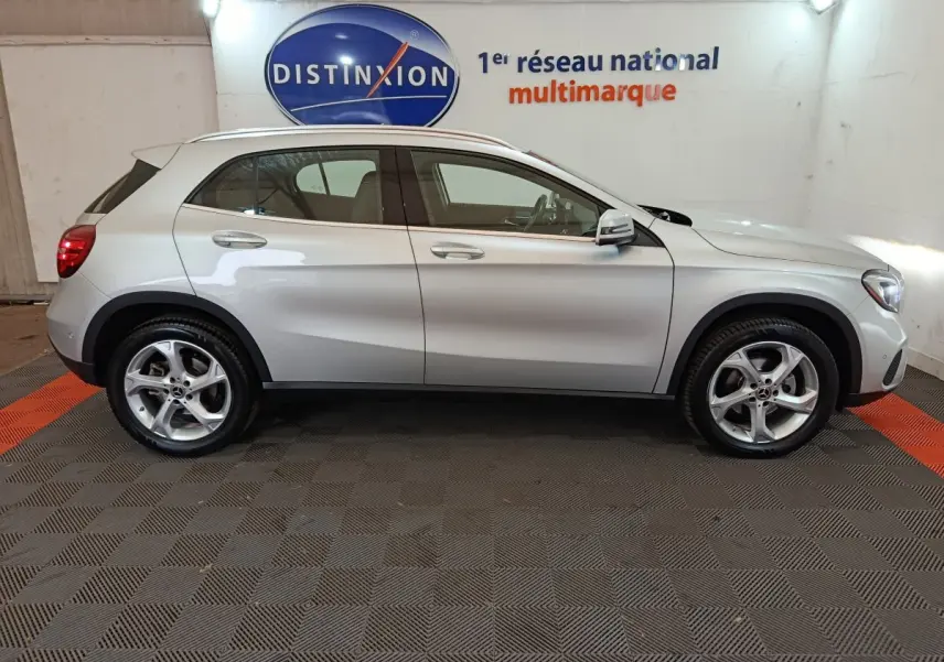 Vue latérale droite d'un Mercedes GLA 200 d gris clair, avec jantes alliage et rétroviseurs électriques dans un showroom.