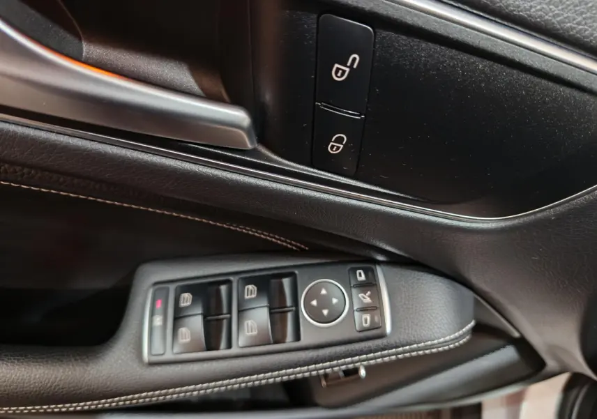 Gros plan sur la porte côté conducteur du Mercedes GLA 200 d gris clair, avec commandes électriques et poignée argentée.