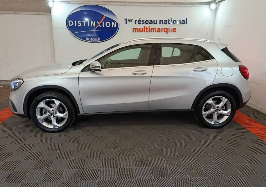 Profil droit d'un Mercedes GLA 200 d Business Executive gris clair, avec jantes alliage et rétroviseurs électriques, en intérieur showroom.