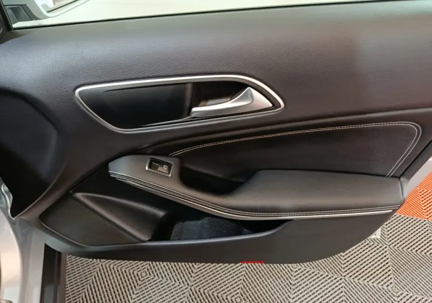 Vue rapprochée de la porte côté gauche d'une Mercedes GLA 200 d gris clair avec garniture noire et surpiqûres blanches.