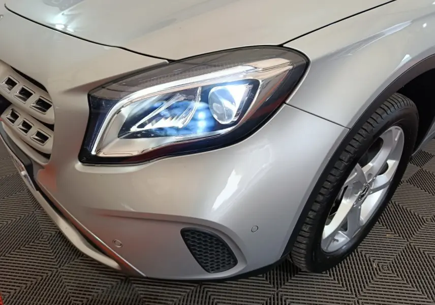 Gros plan sur l'avant droit gris clair du Mercedes GLA 200 d avec phare LED allumé et jante alliage visible.