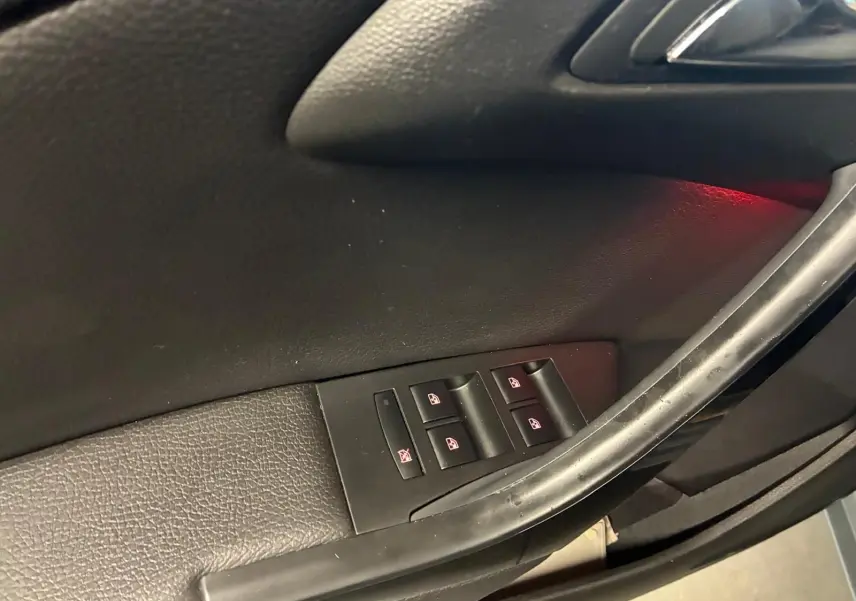 Gros plan sur les commandes des vitres électriques côté gauche de la porte d’une Opel Astra gris 2015.