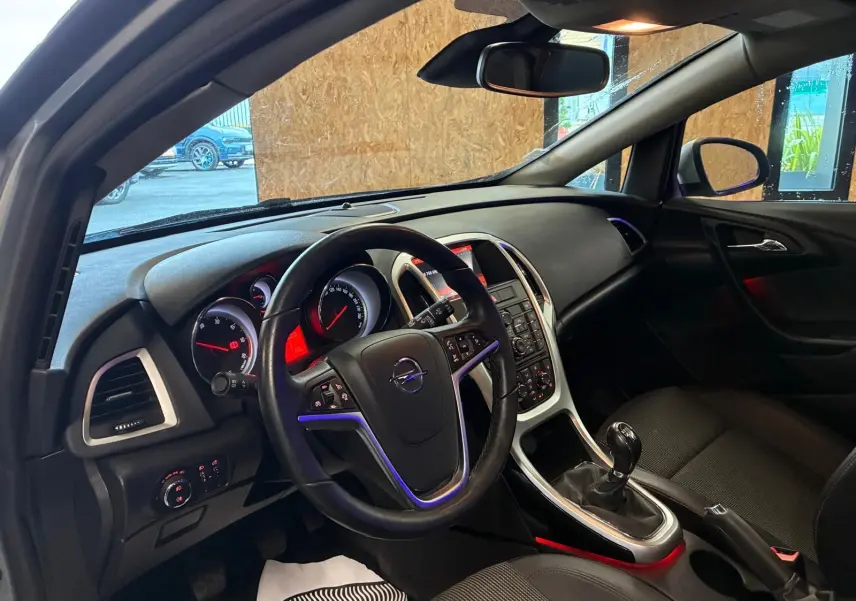 Intérieur de l’Opel Astra 1.6 CDTI 2015, vue côté conducteur, tableau de bord noir avec console centrale et boîte manuelle.