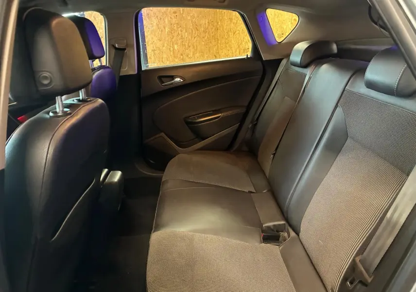 Vue intérieure arrière droite de l’Opel Astra 2015, sièges en tissu et cuir noir, espace passagers visible.