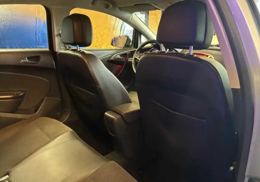 Vue intérieure arrière de l'Opel Astra gris 2015, montrant les sièges avant en cuir noir et la banquette arrière.